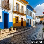 관광학과 사회학의 관계 - A vibrant street scene in a traditional Portuguese village, showcasing diverse tourists interacting ...